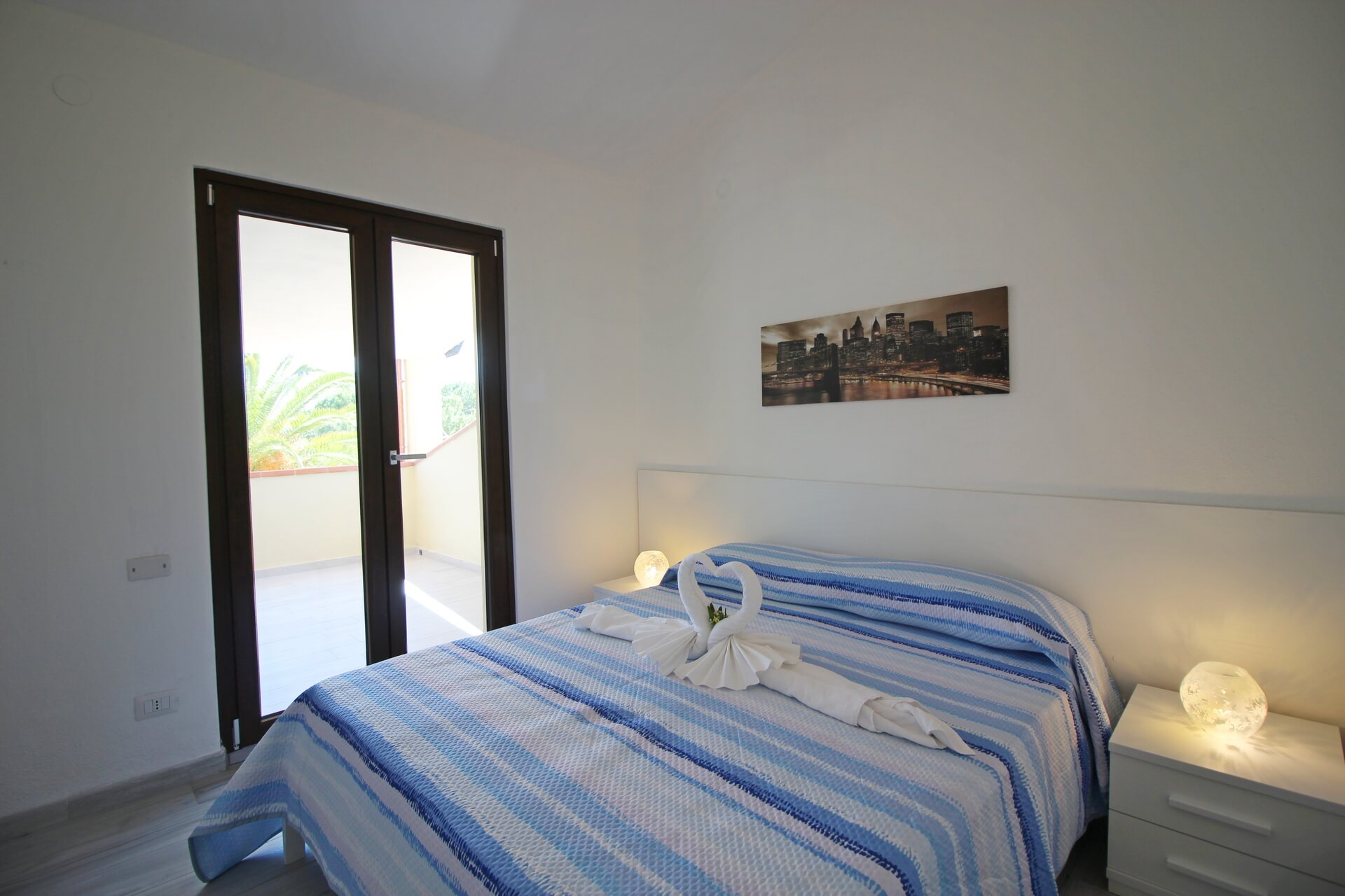Letto matrimoniale con lenzuola a righe blu e bianche e decorazione di asciugamani a forma di cigni