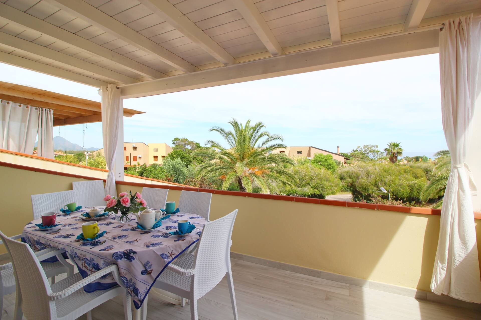 Veranda della Casa Corina con vista sul giardino e tavolo apparecchiato per la colazione