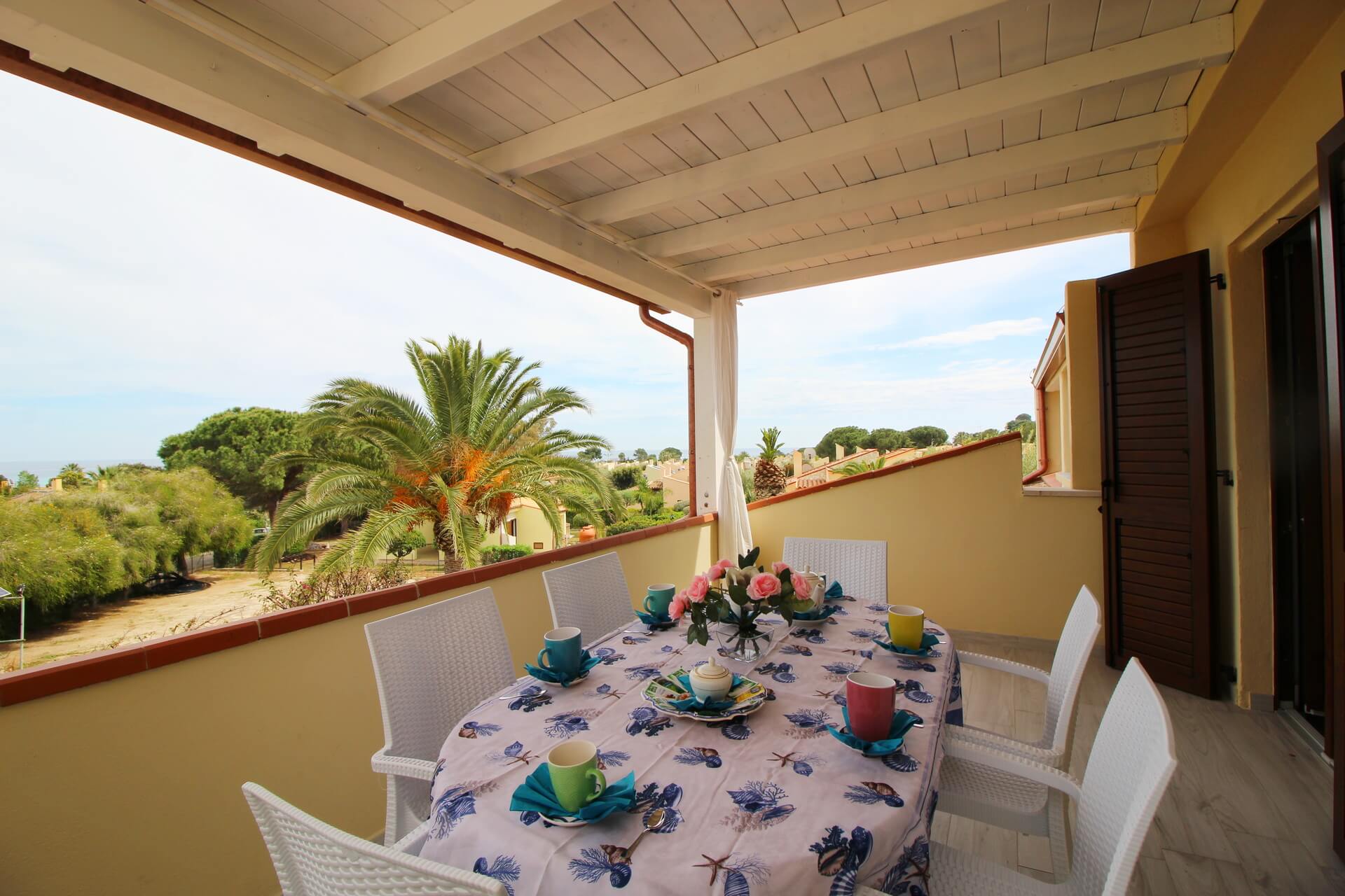 Veranda della Casa Corina con tavolo apparecchiato e vista sulle palme
